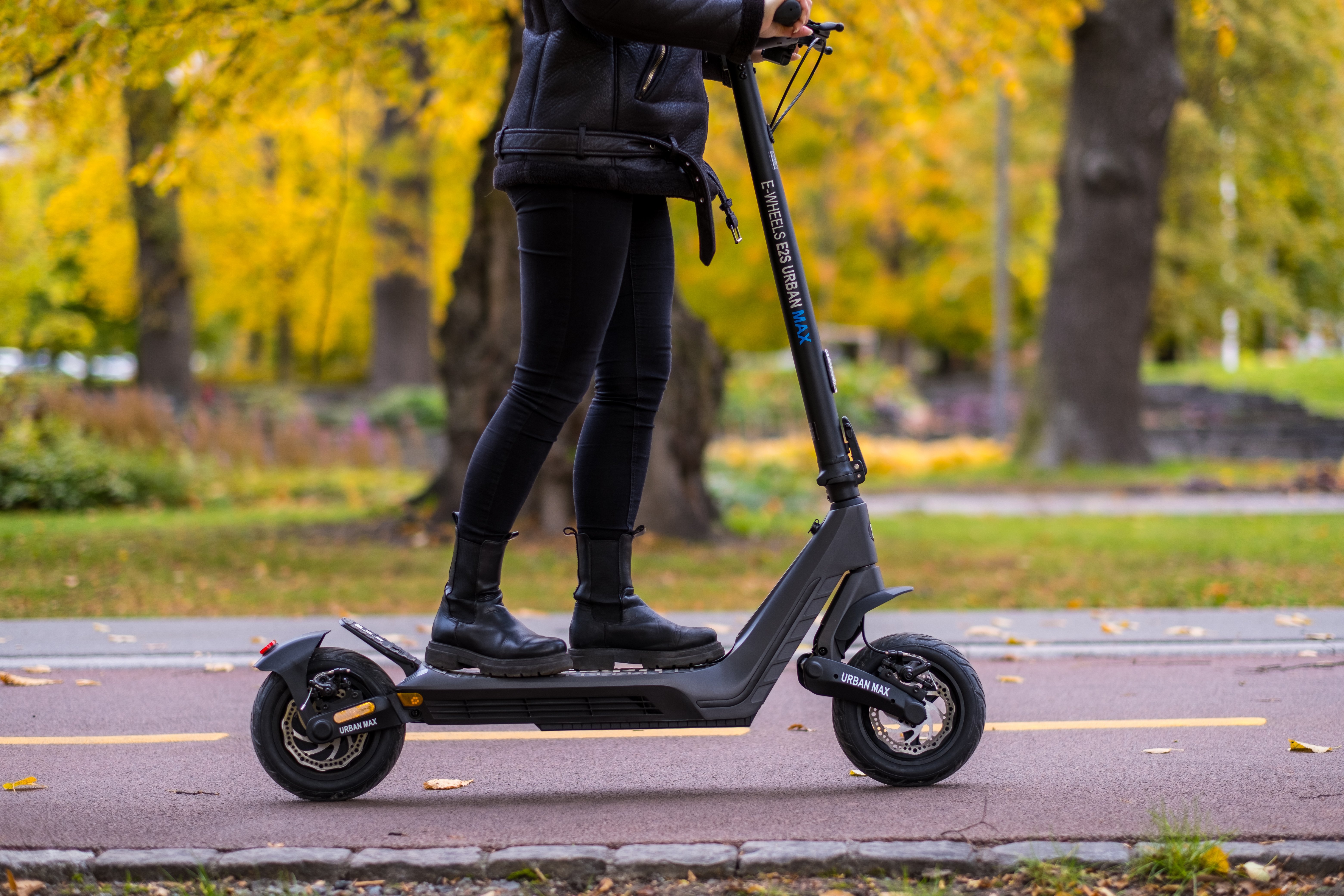 E2S V2 Urban Max el-sparkesykkel fra E-Wheels. Bildet er tatt utendørs, en dame kjører på sparkesykkelen.jpg